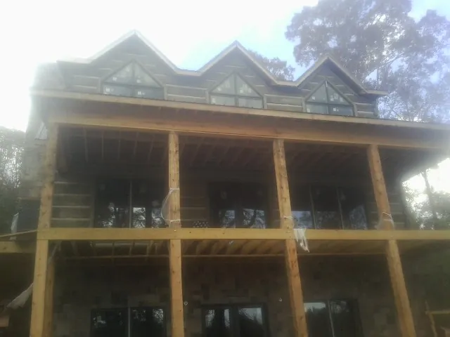 Dormers and porch framing on a large log home under construction — Roof Coating work by our crew in Guinda