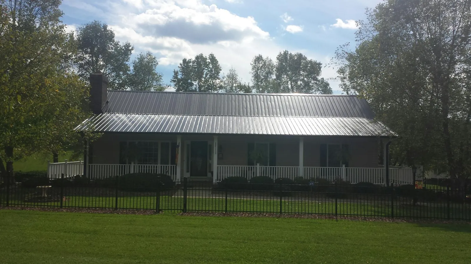 Gray metal roof on a brick ranch with a full width front porch — Gutter Guard Installation work by our crew in Guinda