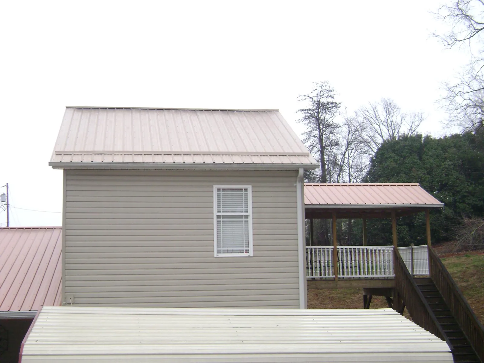 Tan metal roofs on a two story addition and attached porch, from a Roof Replacement job in Guinda