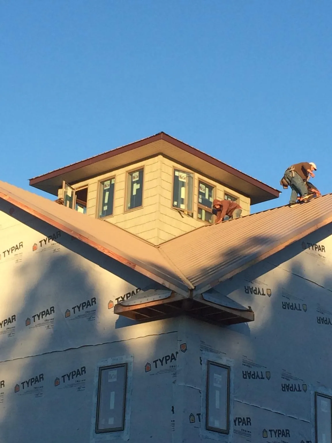 Roofers working around a rooftop cupola on a new metal roof at sunset — Roof Waterproofing in Guinda by Roofing Brothers